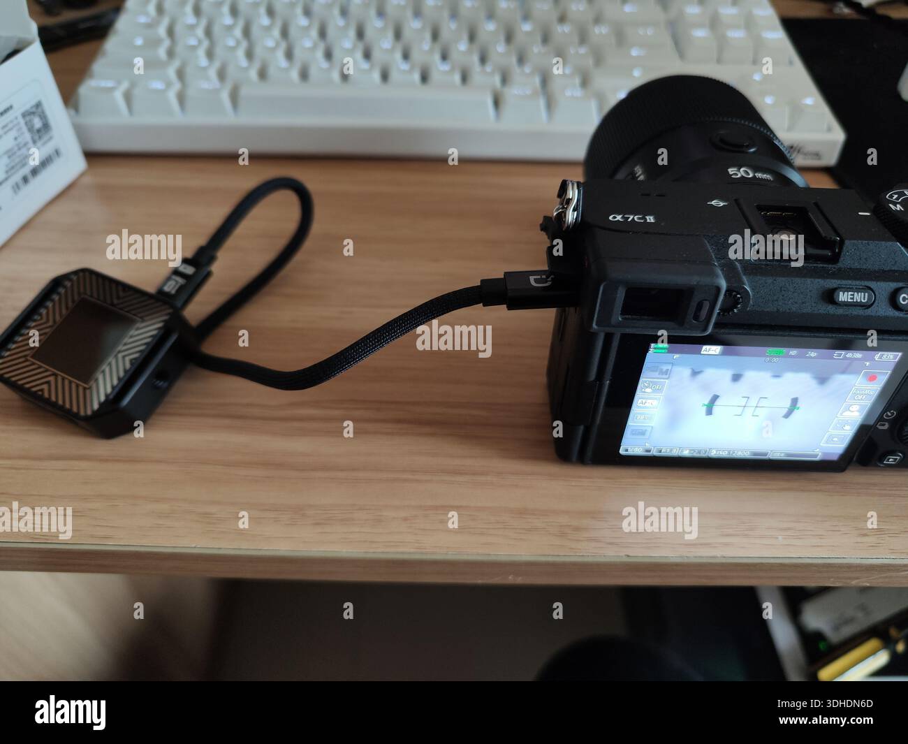 Digital camera connected to external device via USB cable on desk Stock Photo