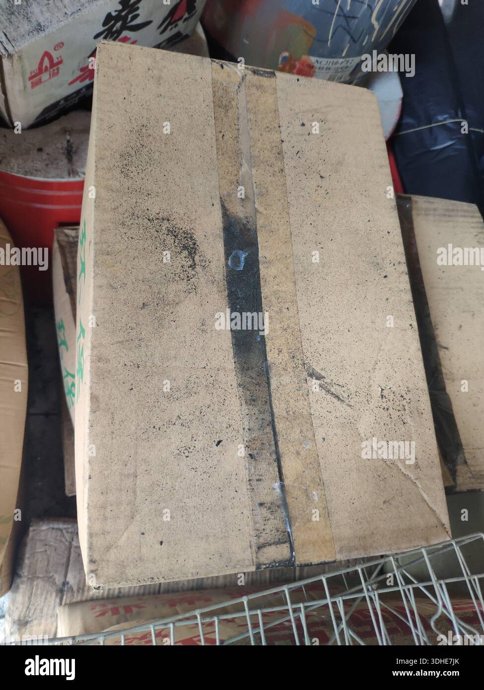 Worn cardboard box with tape and stains, stacked among other items Stock Photo