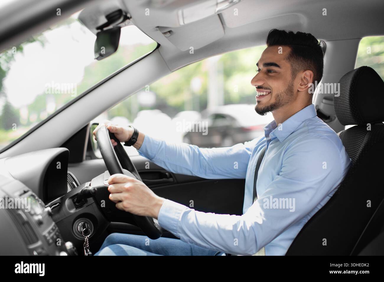 Joyful arabic guy driving nice auto, side view Stock Photo
