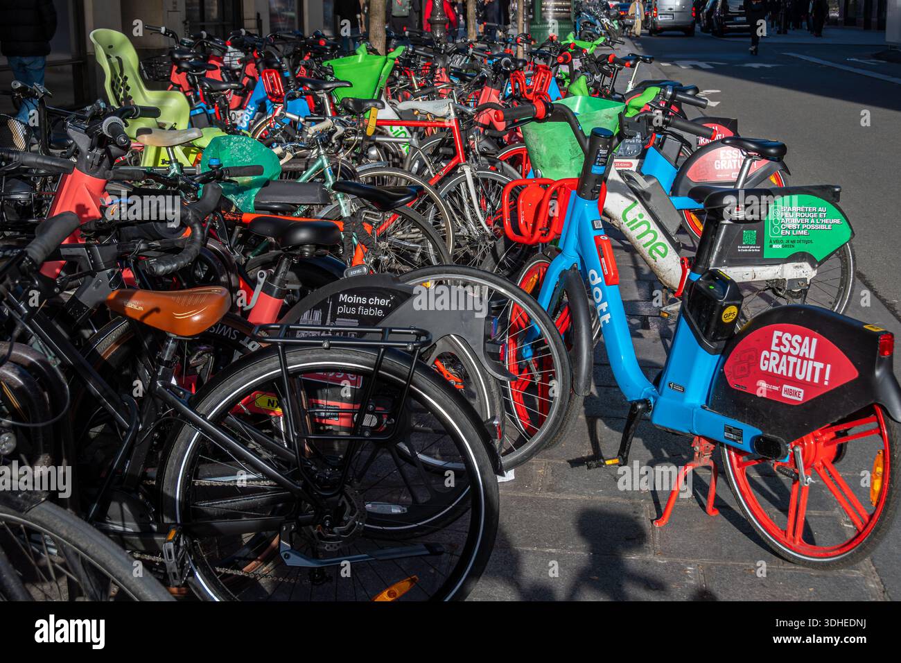 Many self-service bicycles belonging to different dockless bike rental and shared mobility services parked in a chaotic way on a street of Paris Stock Photo