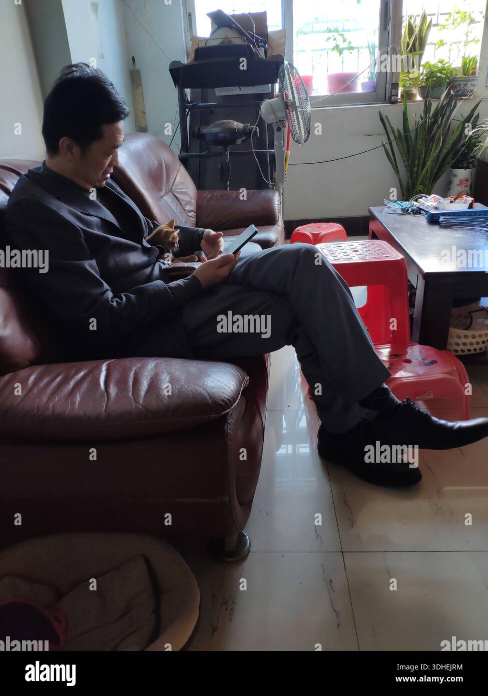 Man sitting on leather sofa using tablet in living room Stock Photo