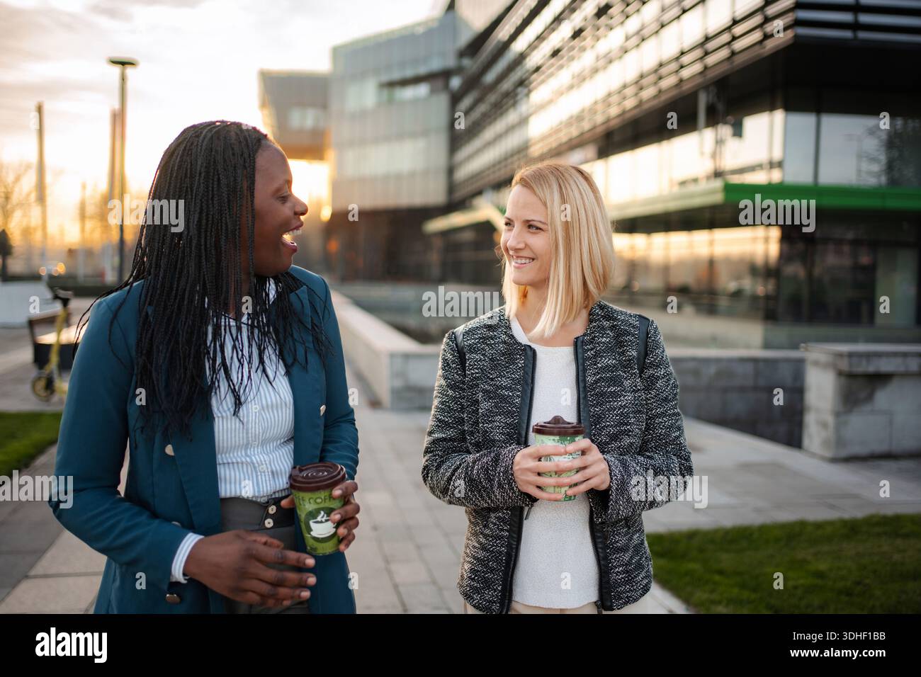 Diverse businesswomen walking, talking, drinking coffee on urban break Stock Photo