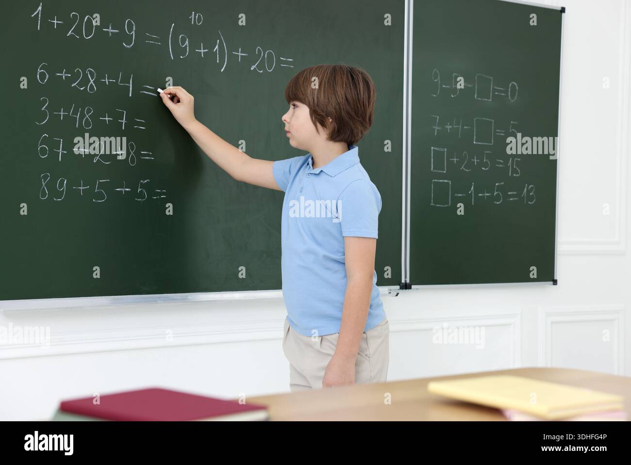 Schoolboy doing math on chalkboard in classroom Stock Photo