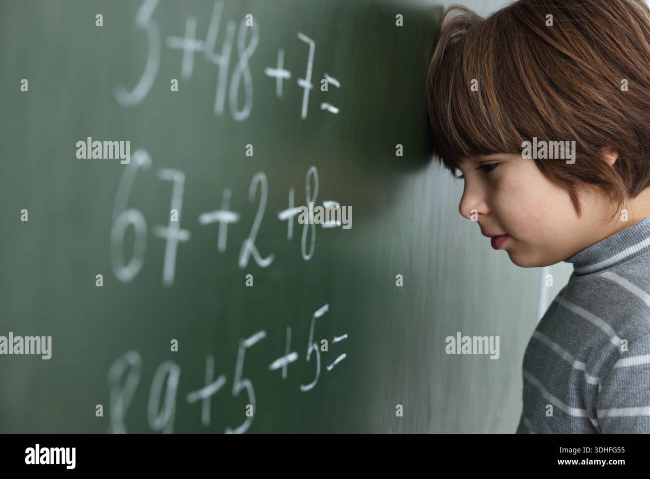 Schoolboy doing math on chalkboard in classroom Stock Photo
