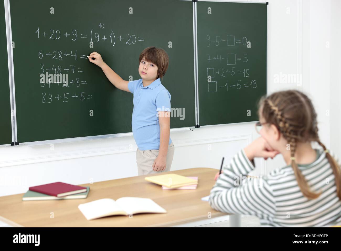 Schoolboy doing math on chalkboard in classroom Stock Photo