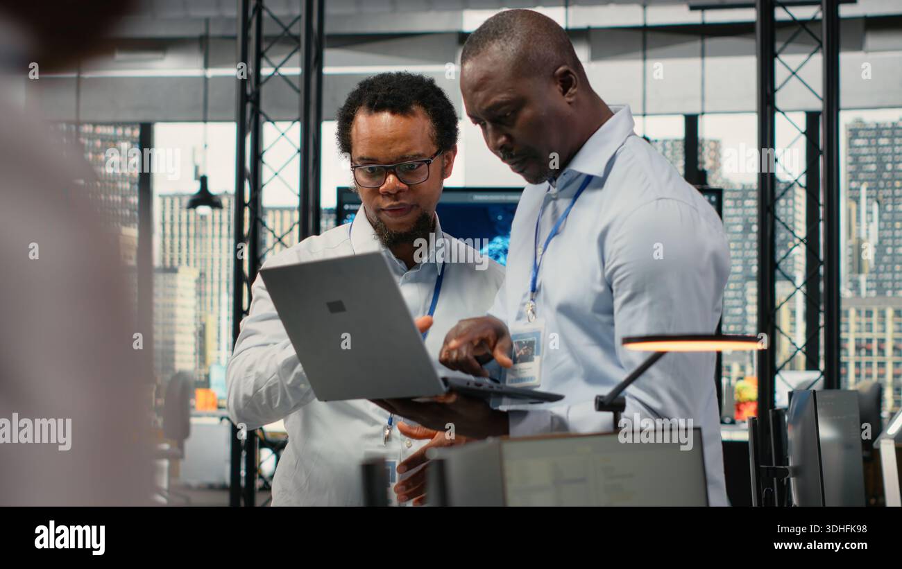 Team of technicians in office doing software development to launch new features. Startup coworkers writing computer programs, doing code testing and quality assurance, camera B Stock Photo
