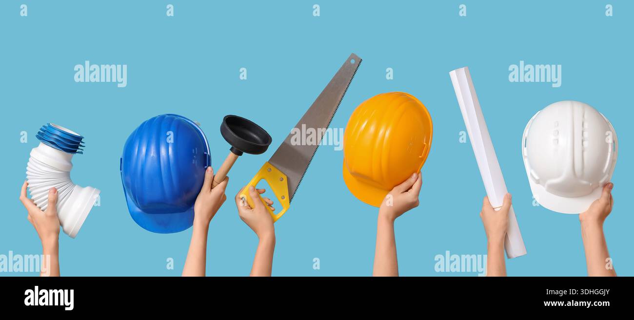 Hands with hardhats and construction tools on blue background Stock Photo