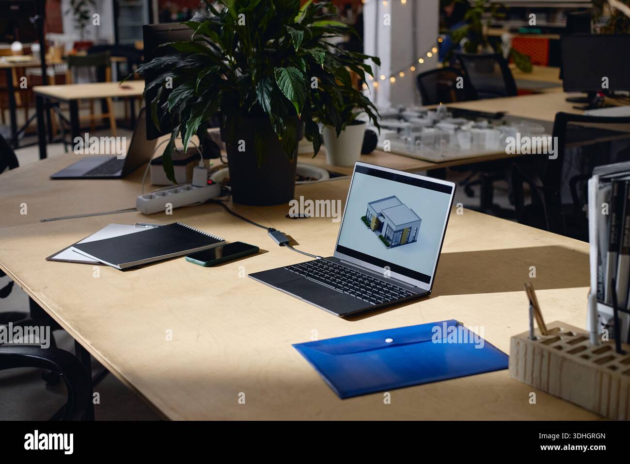 Modern Office Workspace Featuring Laptop Displaying Architectural Rendering Stock Photo