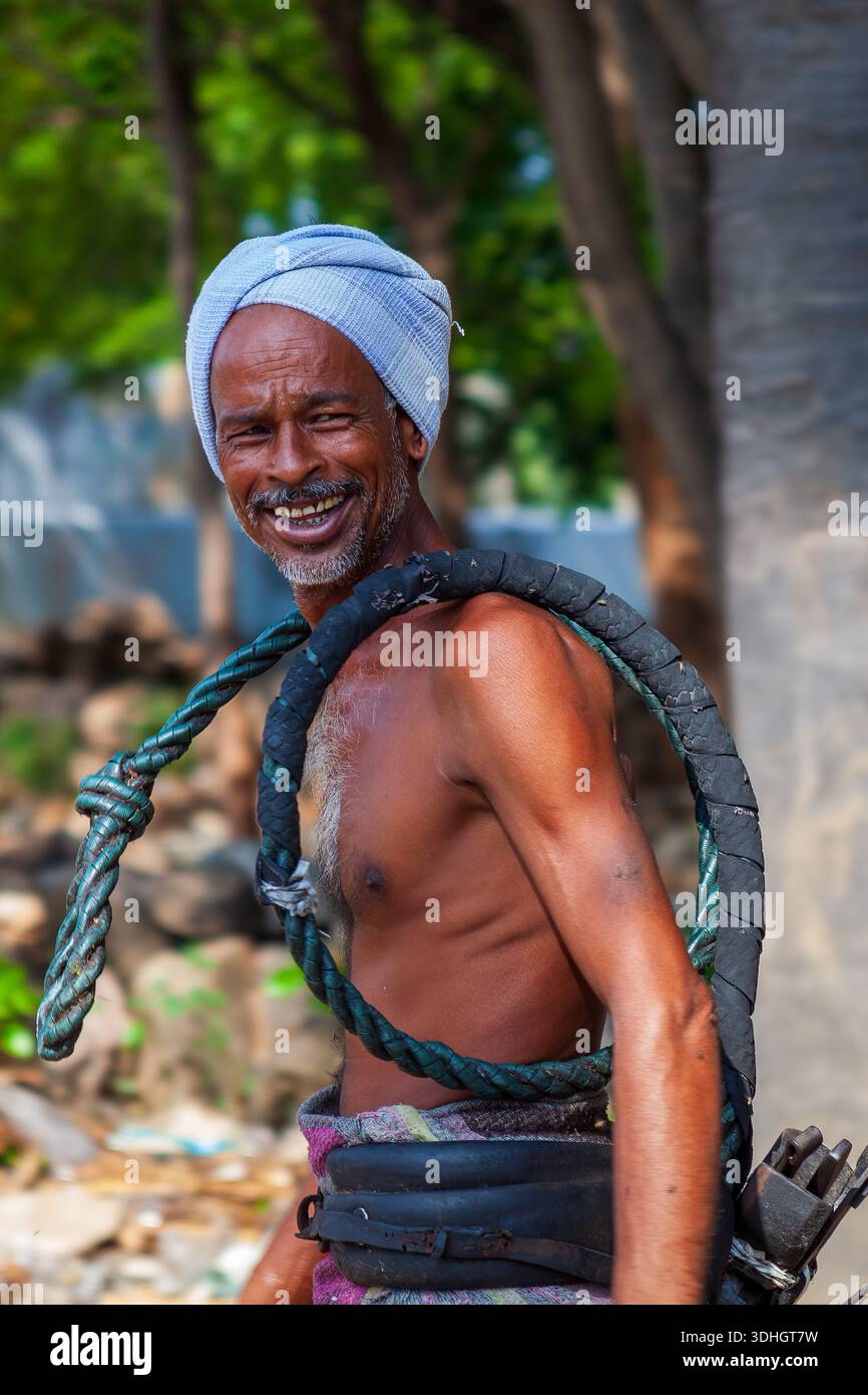 A toddy tapper gives sap collected from a palm tree to a customer outside the village Stock Photo