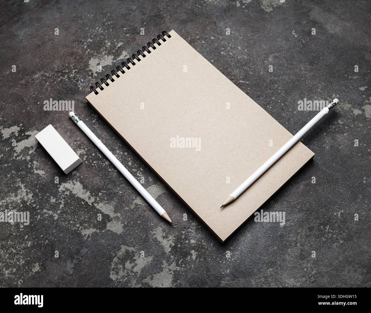 Closed blank kraft notebook, pencils and eraser on concrete surface. Stationery template. Stock Photo
