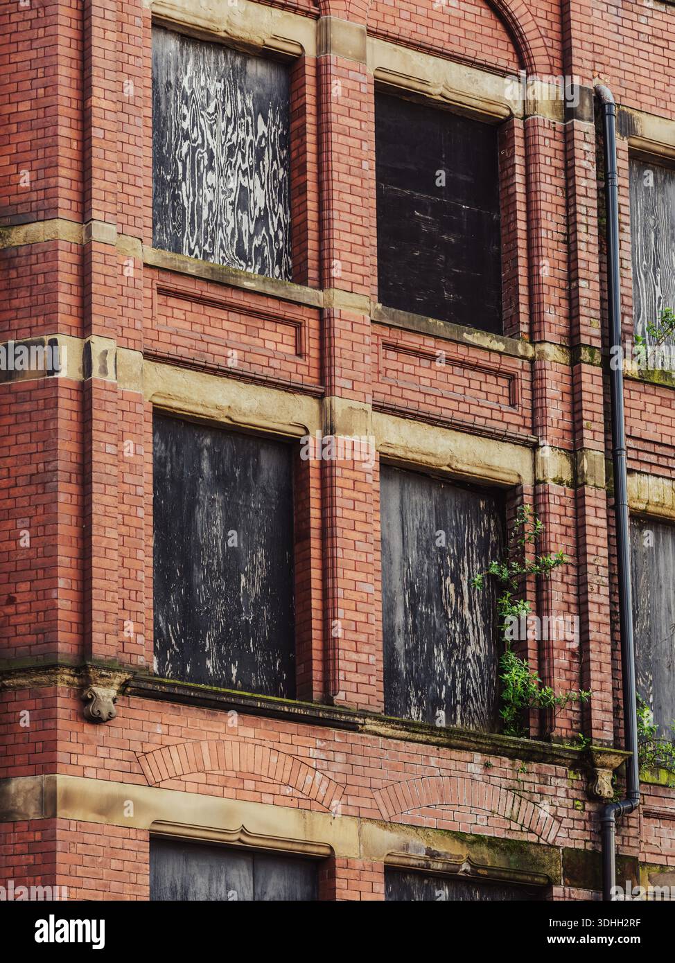 Old red brick building with boarded-up windows showing signs of decay ...