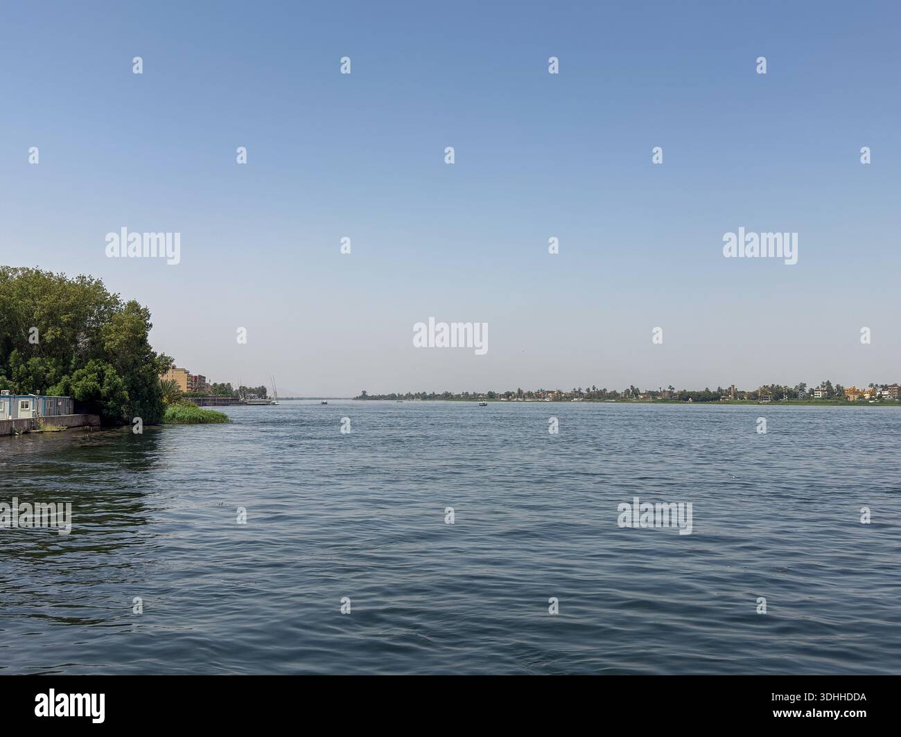 Ägypten Nil: Dorf mit Turm, Palmen und blauem Boot am Ufer - Smartphone Captured Stock Image