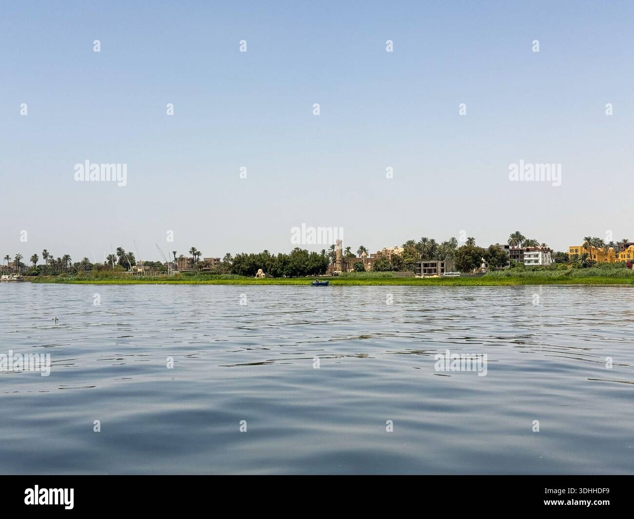 Ägypten Nil: Dorf mit Turm, Palmen und blauem Boot am Ufer - Smartphone Captured Stock Image