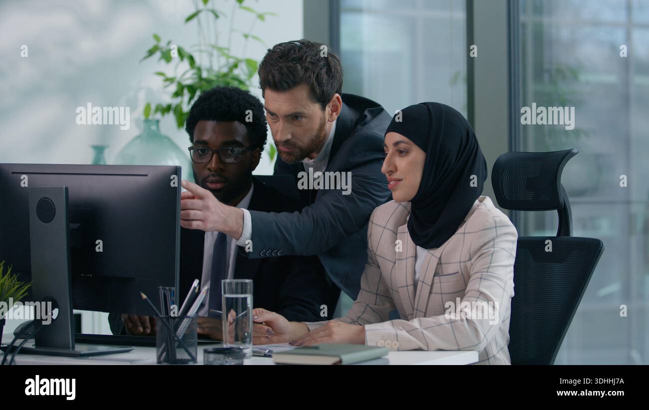 Multicultural business colleagues collaborating in modern office multiracial co-workers working African American male woman in hijab and Caucasian man Stock Photo