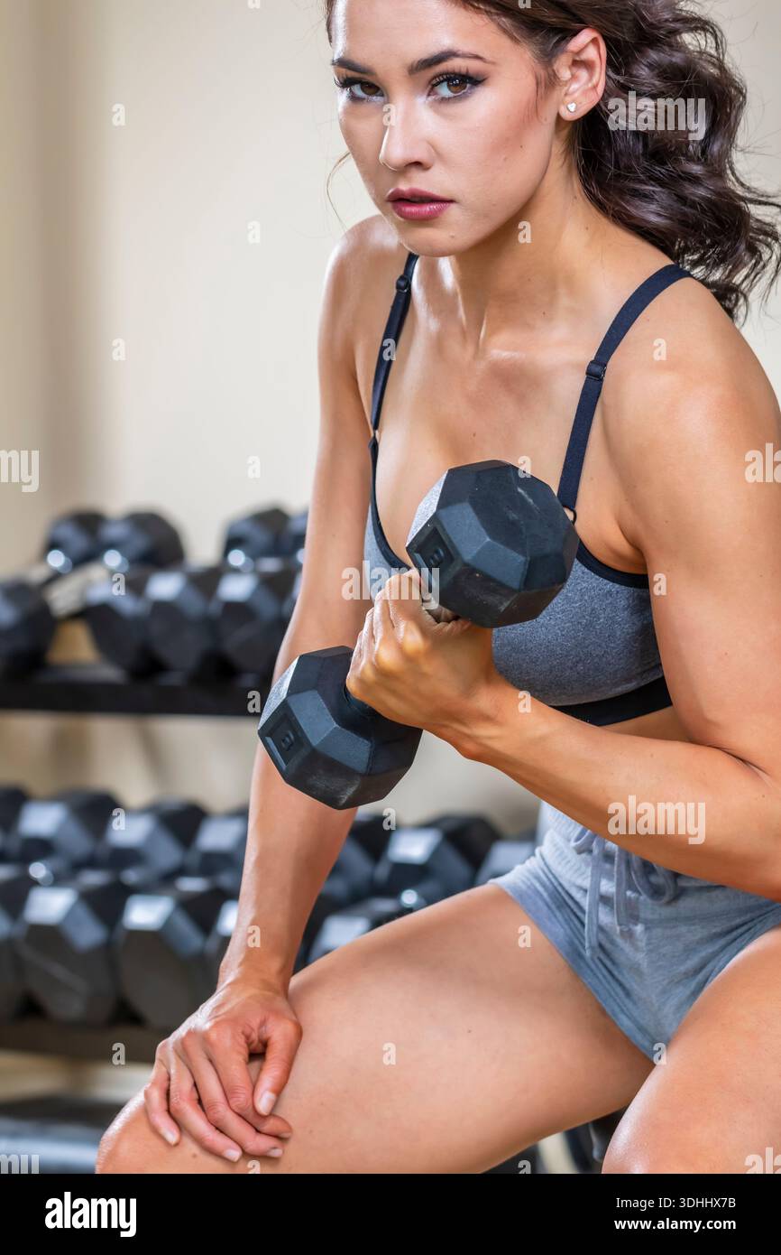 A young woman trains in her home gym, focused and energized, performing exercises with determination and strength, setting a powerful tone for her day Stock Photo