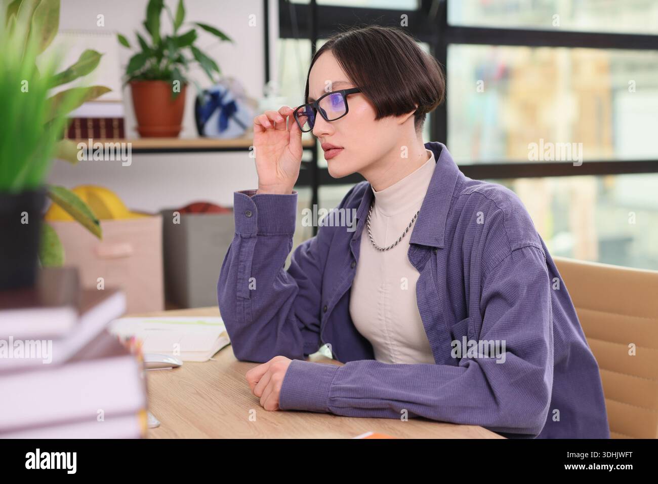Engaging work session in a bright, modern office featuring a thoughtful young professional Stock Photo