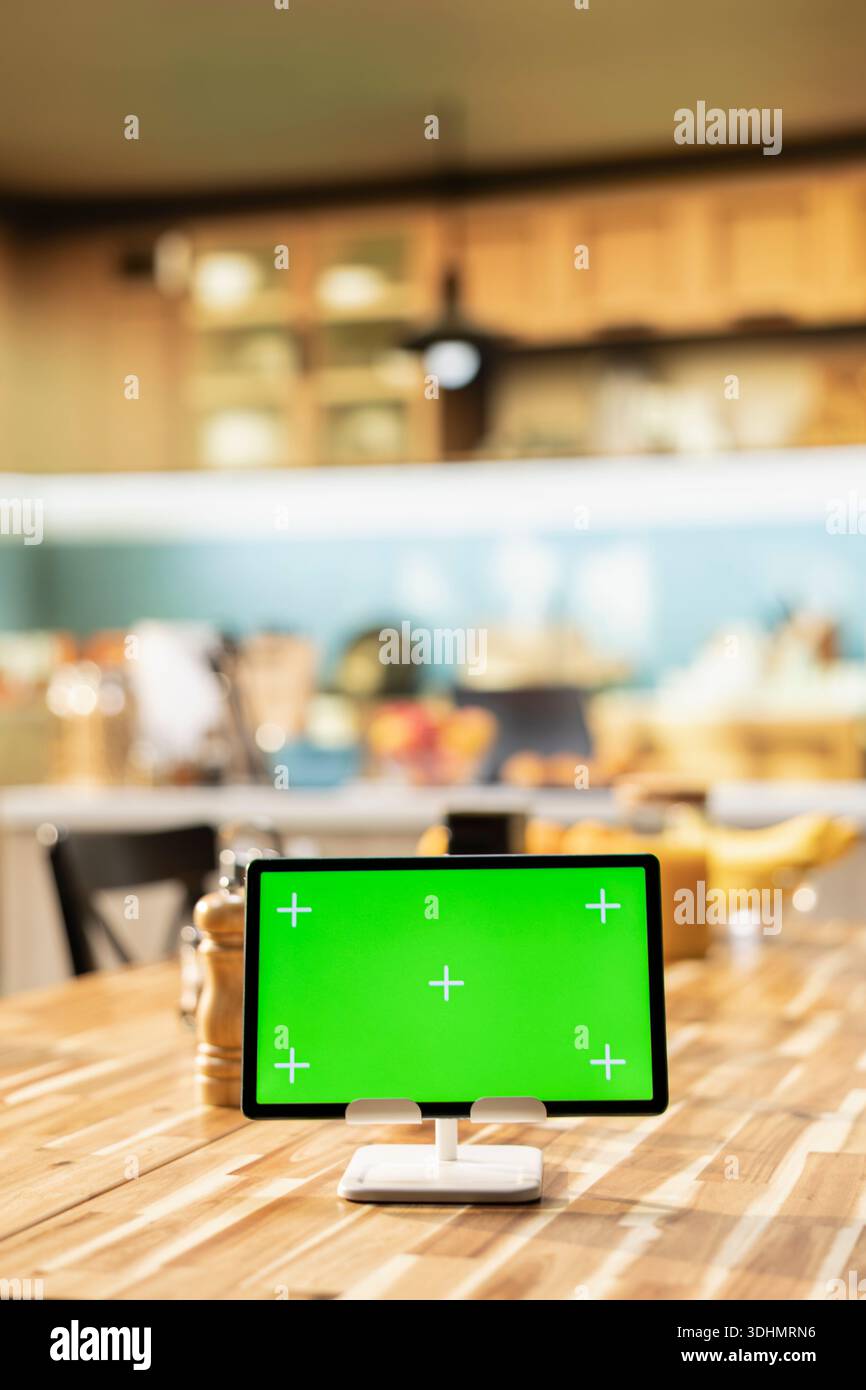 Isolated chroma key on tablet in rustic wooden stylish kitchen space decorated with modern appliances and kitchenware, cozy atmosphere with interior design at the dining table. Stock Photo