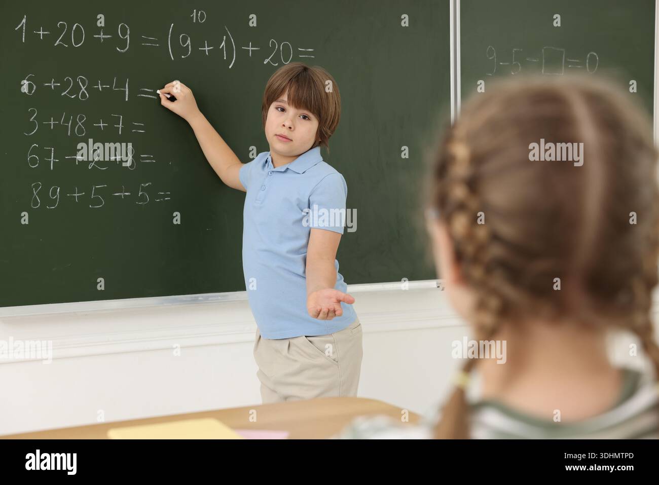 Schoolboy doing math on chalkboard in classroom Stock Photo
