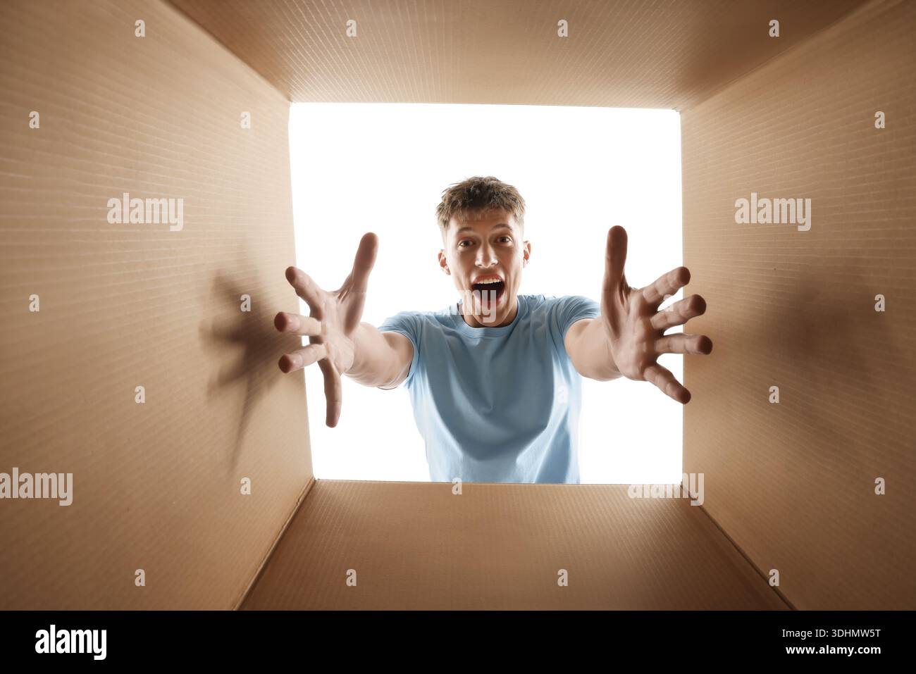 Man looking into cardboard box against white background, view from inside package Stock Photo