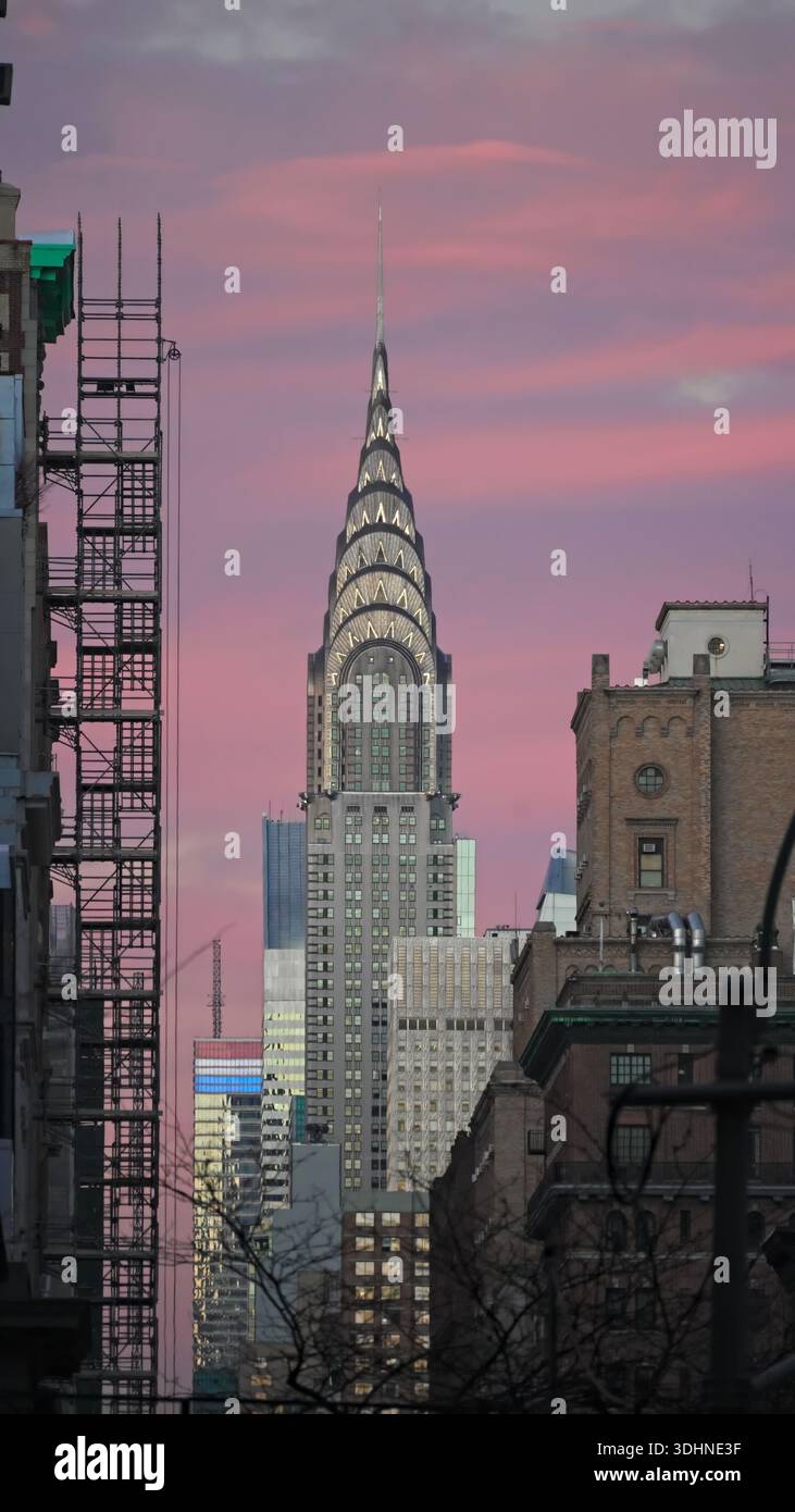 New York, NY- Dec. 20, 2025: Manhattan neighborhood buildings with Chrysler Building skyline at dusk with pink sunset sky. Vertical orientation. Stock Photo