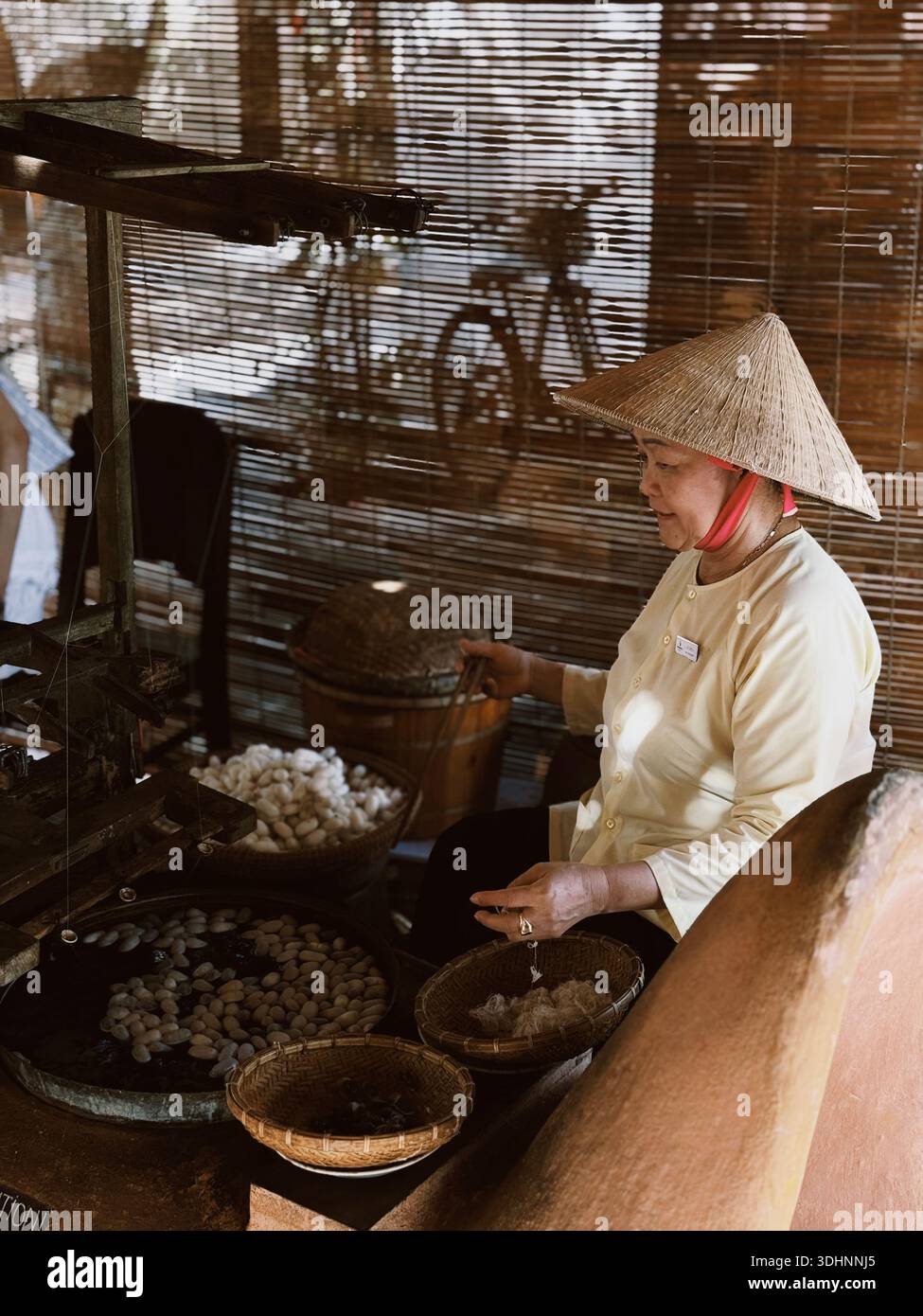Vietnamese woman demonstrating traditional silk making process at a cultural heritage site in Vietnam - Smartphone Captured Stock Image