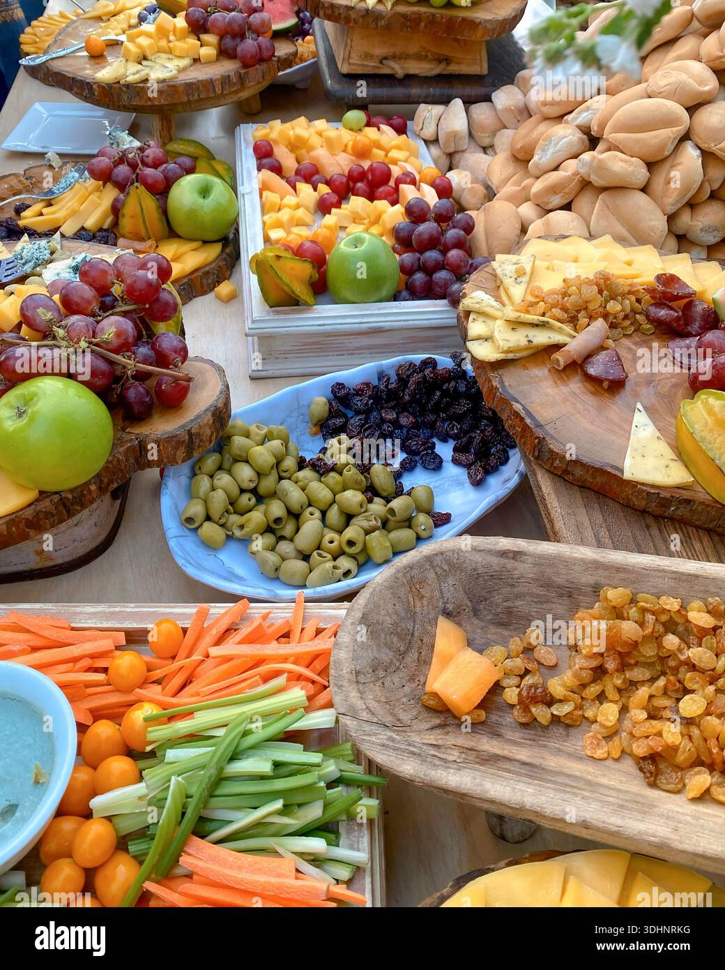 Gourmet buffet table featuring cheeses, fresh fruits, and appetizers at an outdoor wedding reception - Smartphone Captured Stock Image