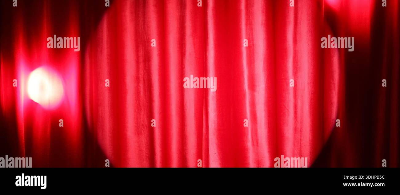 Shining spotlight on red curtain Stock Photo