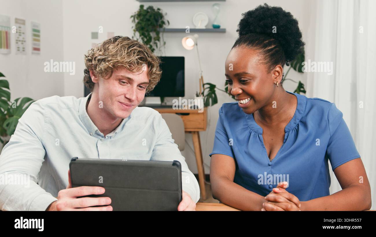 Two Friends Collaborate At A Modern Startup Desk Using Tablet In A Bright Office Stock Photo
