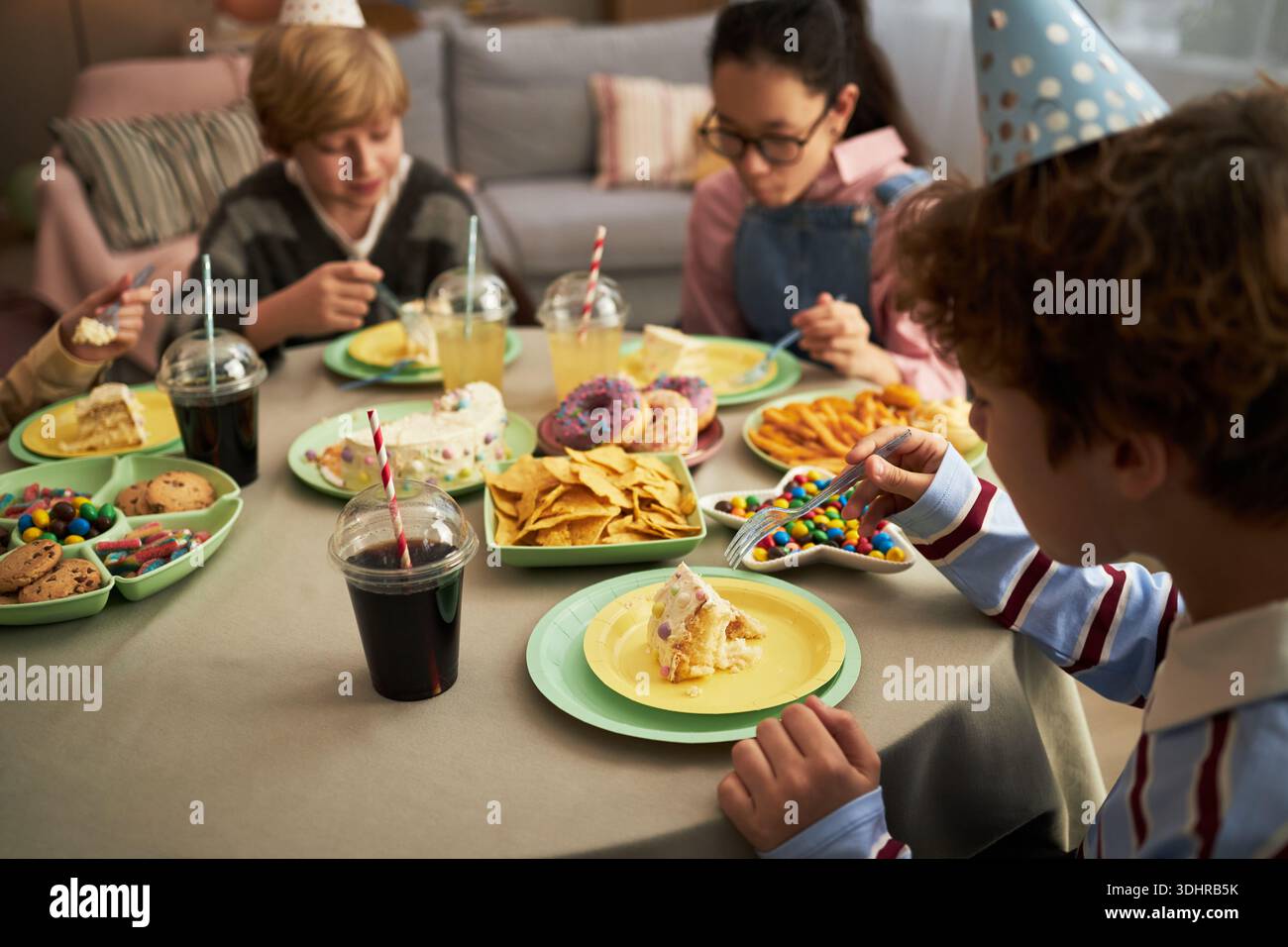 Group of Caucasian and multiethnic children wearing party hats sitting ...