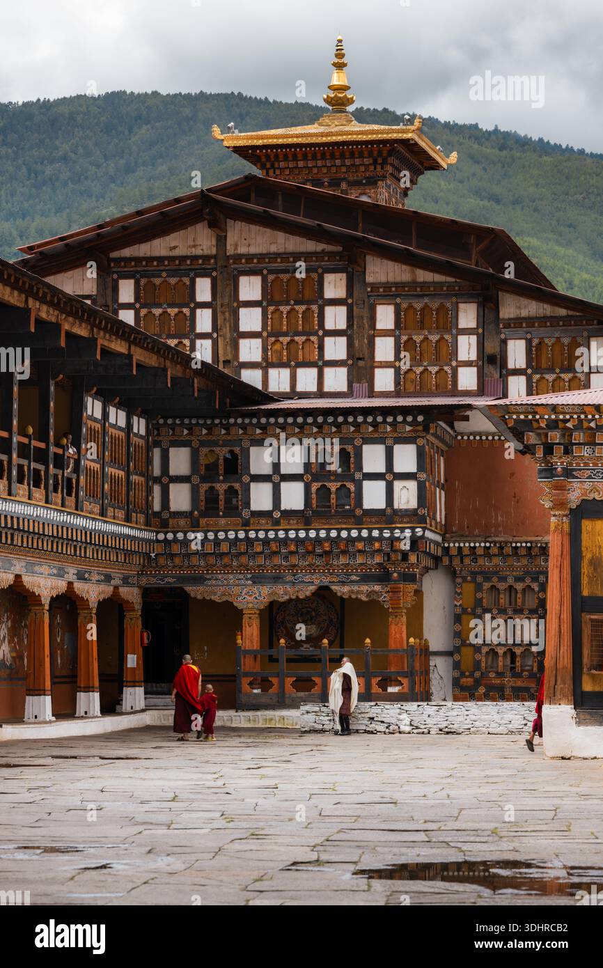 View of ornate architecture with intricate wooden details and gold accents, monks walking in traditional robes, creating a serene yet vibrant scene, P Stock Photo
