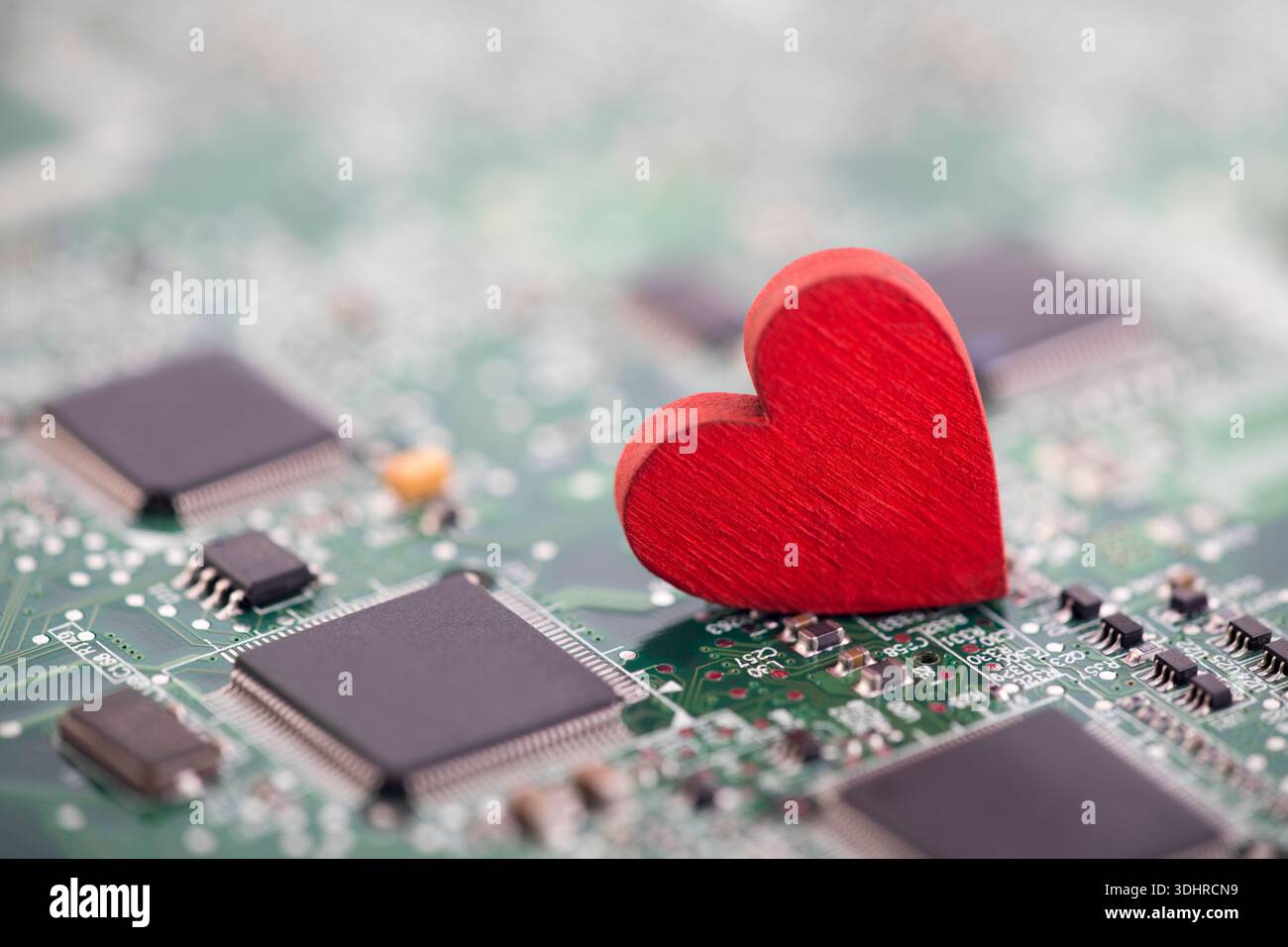 Small red heart on computer circuit board. Internet dating concept. Stock Photo