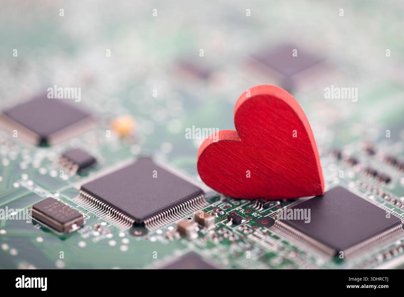 Small red heart on computer circuit board. Internet dating concept. Stock Photo