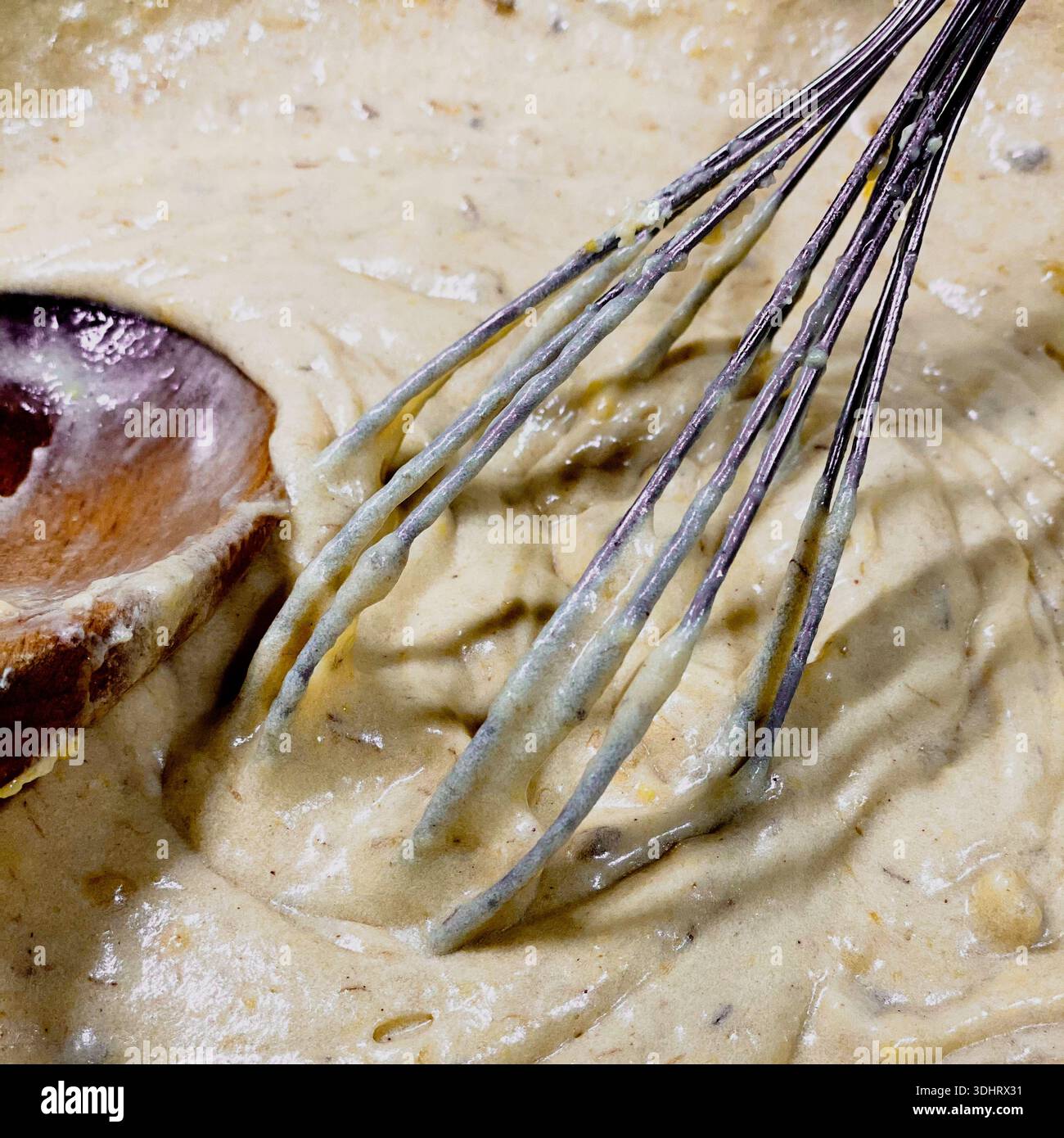 A pancake batter being mixed with a metal whisk and wooden spoon - Smartphone Captured Stock Image