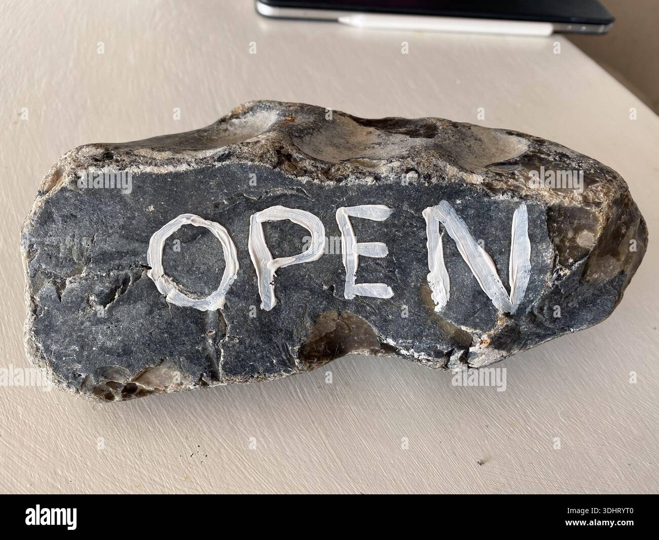 A flint "rock" with the word "open" painted on it - Smartphone Captured Stock Image