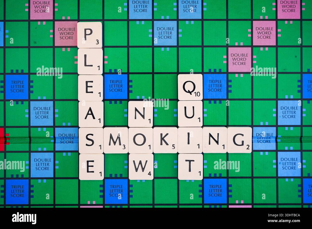 PLEASE QUIT SMOKING NOW words spelt out on a UK Scrabble board. Stock Photo
