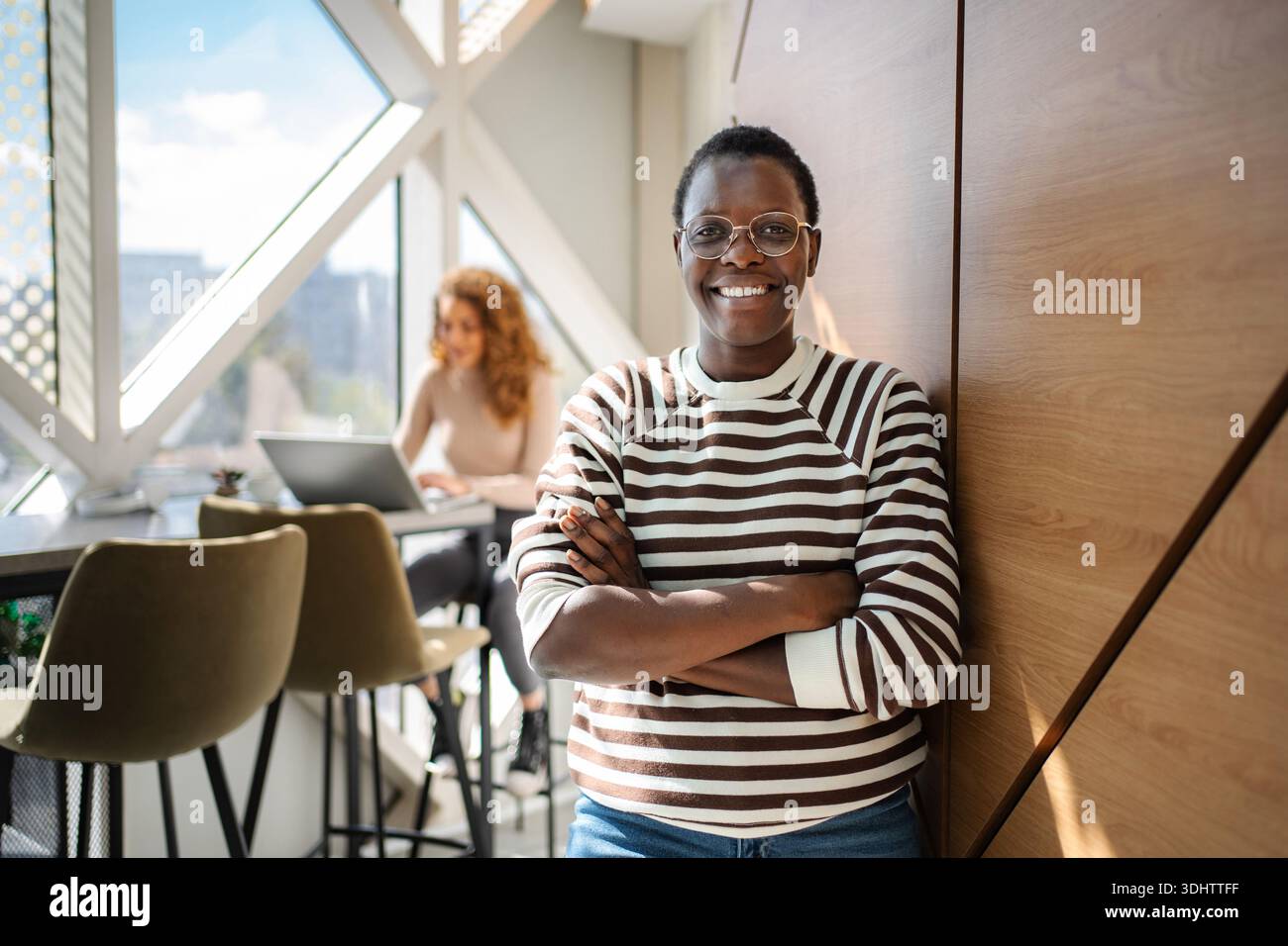 Black woman smiling confidently in modern office space Stock Photo