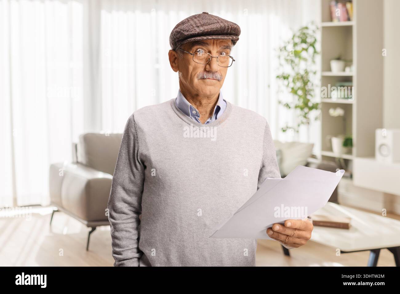 Senior man holding documents and thinking at home Stock Photo