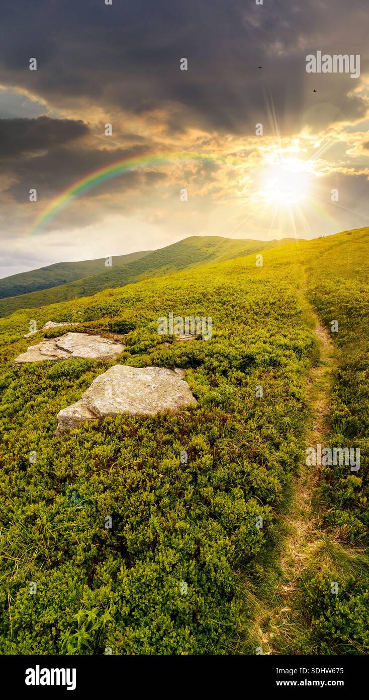 hiking trail through mountain landscape at sunset. mountain range under sky with clouds in evening light. scenery with green grass and rolling hills. Stock Photo