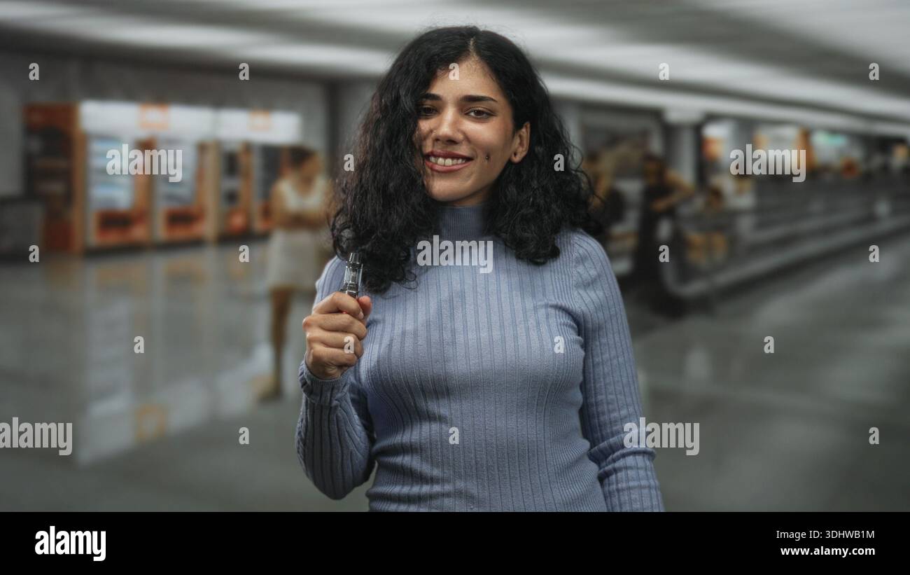 Arab woman holding a vape device and smiling while standing in an airport  terminal with blurred travelers and vending machines; relaxed independence  Stock Photo - Alamy