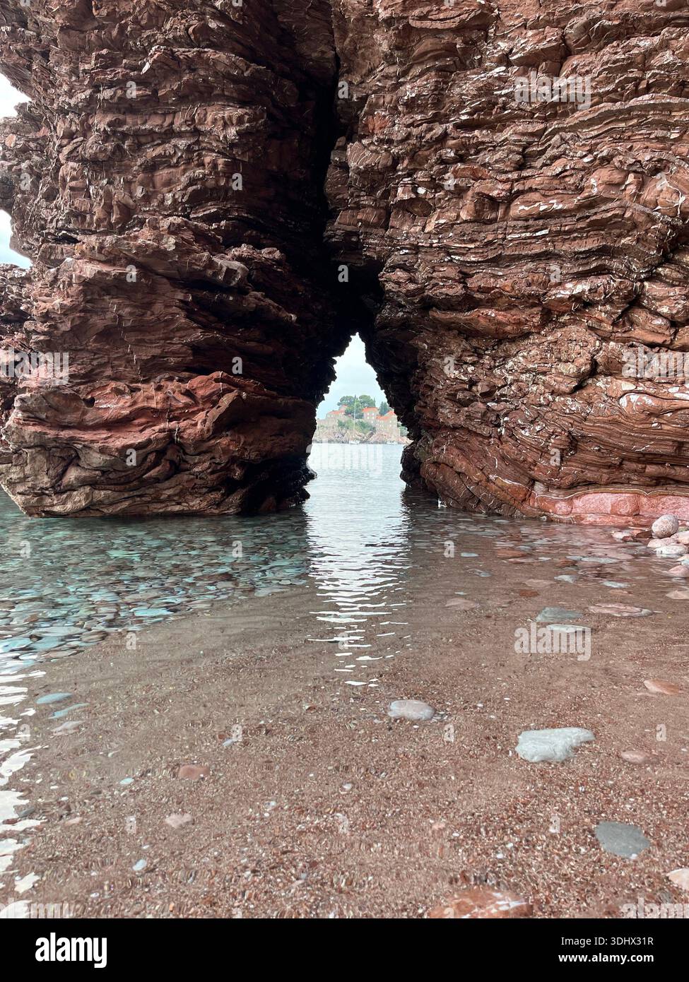Mystical view of Sveti Stefan Island through a rock arch - Smartphone Captured Stock Image