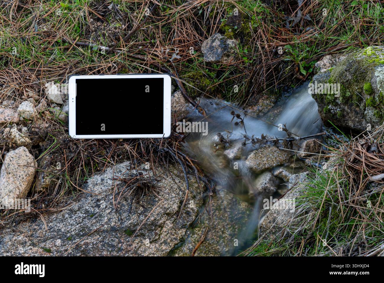 Modern tablet placed beside river outdoors Stock Photo
