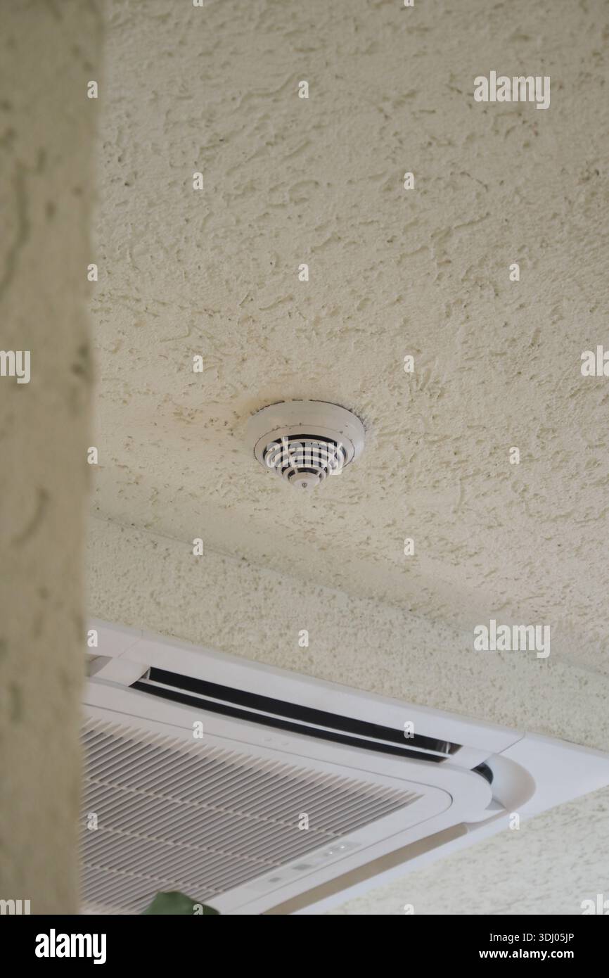 Smoke detector installed on ceiling in indoor area Stock Photo