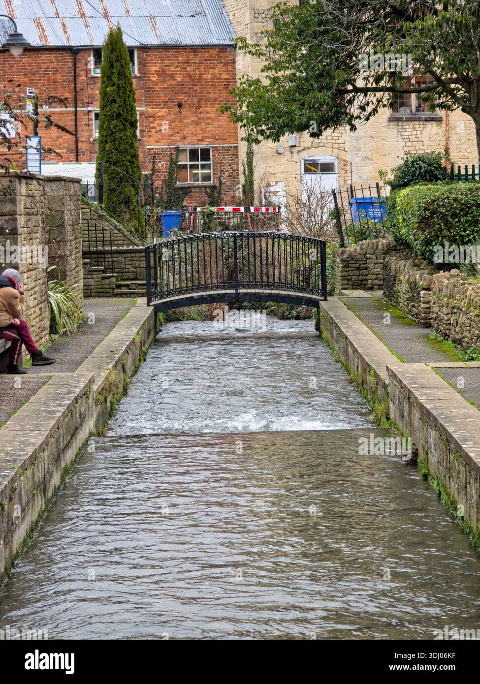 Quaint village stream with small iron bridge in Cotswolds England - Smartphone Captured Stock Image