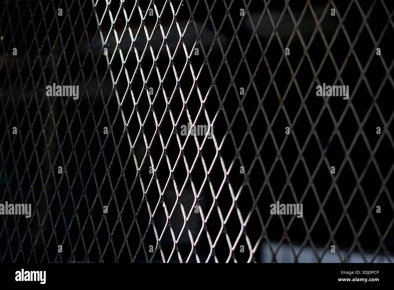 Morning Light Through Perforated Steel Gate, a photograph capturing sunlight filtering through a roof, casting striking shadows on a textured steel ga Stock Photo