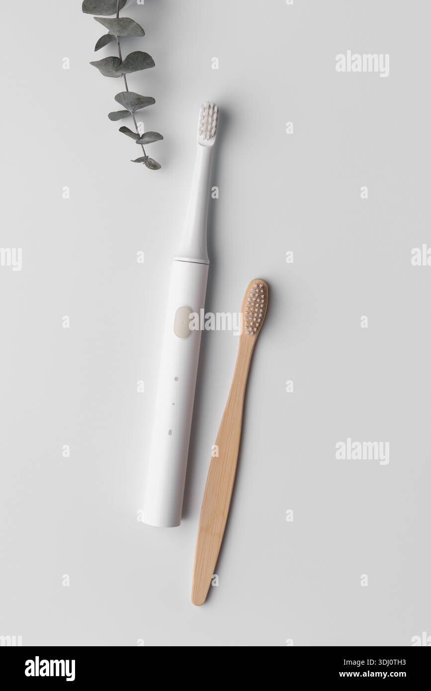 Minimalist flat lay of bamboo and ultrasonic toothbrushes symbolizing conscious lifestyle choice, balance between nature and technology, modern sustai Stock Photo
