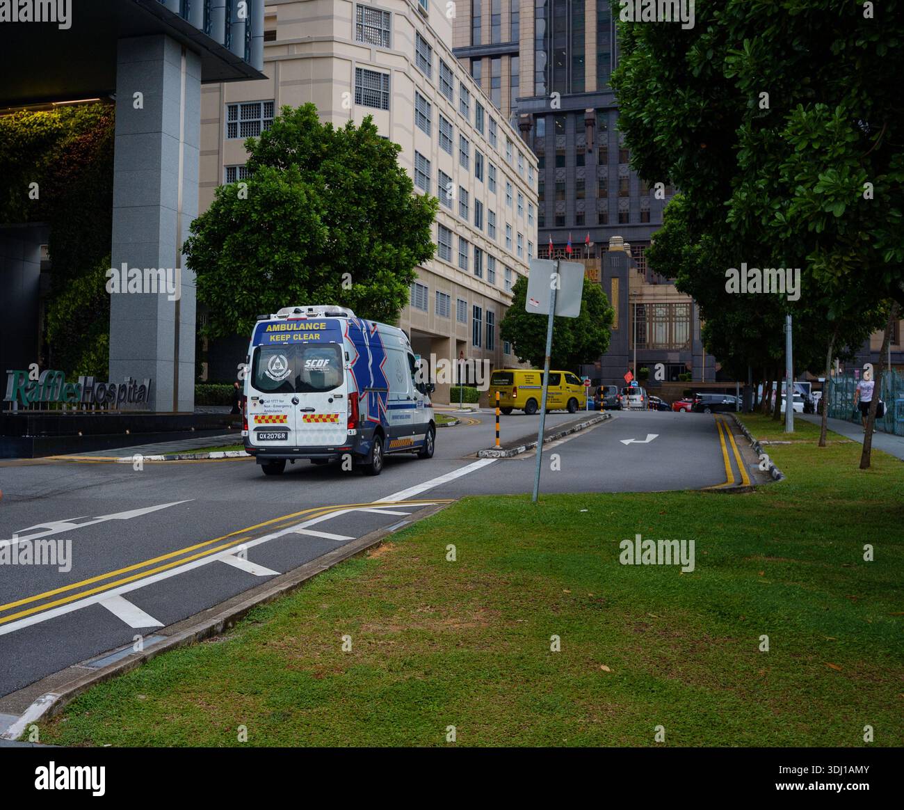An Emergency ambulance vehicle arrives with sirens and flashing lights at Raffles Hosptal Singapore Asia. Stock Photo