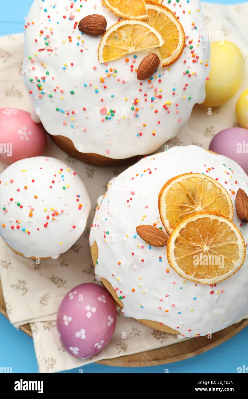 Delicious Easter cakes and eggs on blue table, top view Stock Photo
