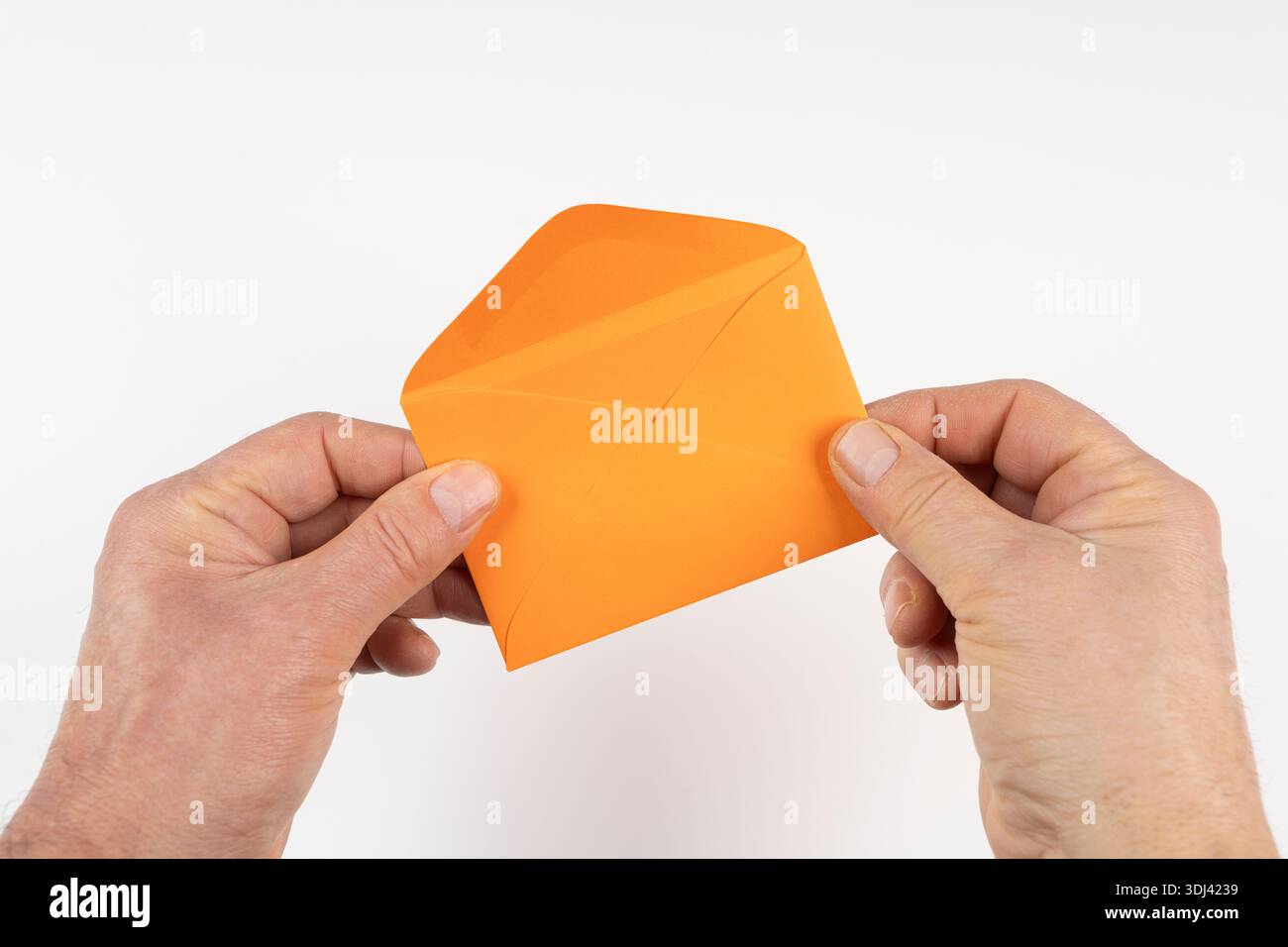 an open orange envelope in the hands on a white surface Stock Photo