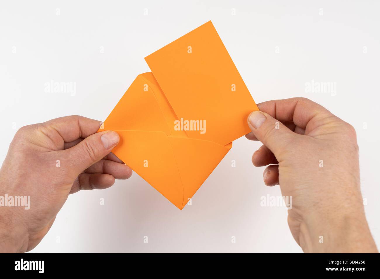 an open orange envelope in the hands on a white surface Stock Photo