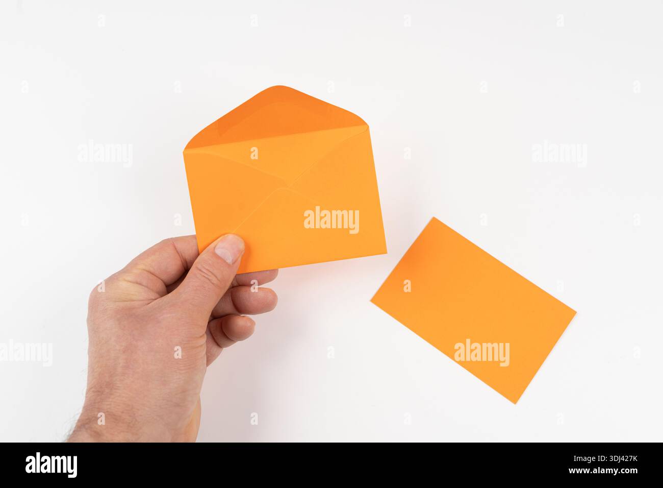 an open orange envelope in the hands on a white surface Stock Photo
